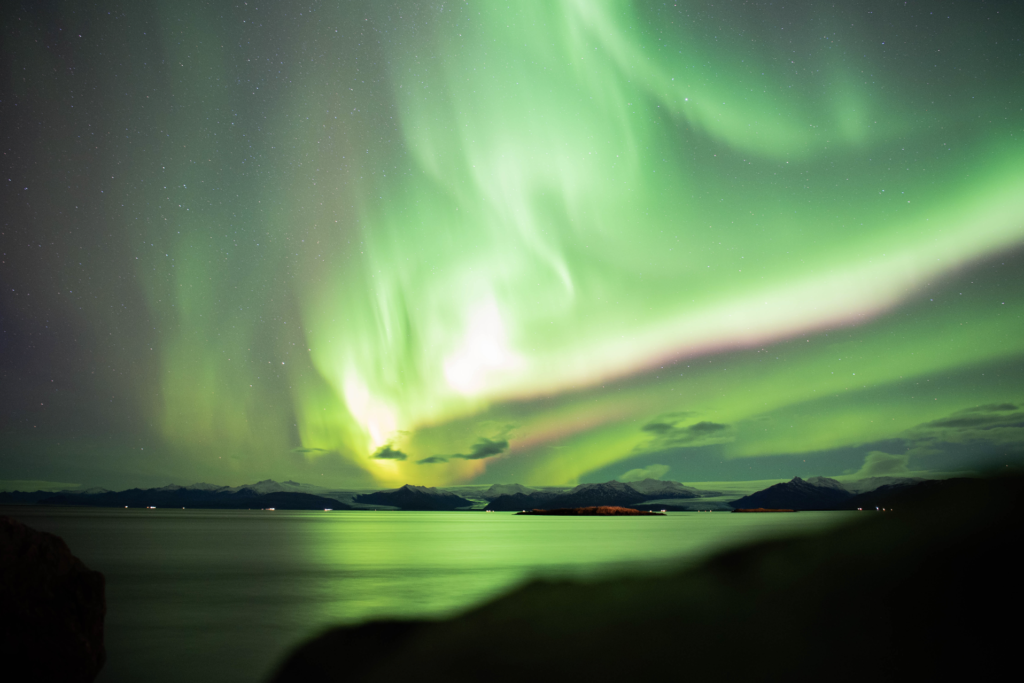 Bright green and pink Northern Lights over a lake